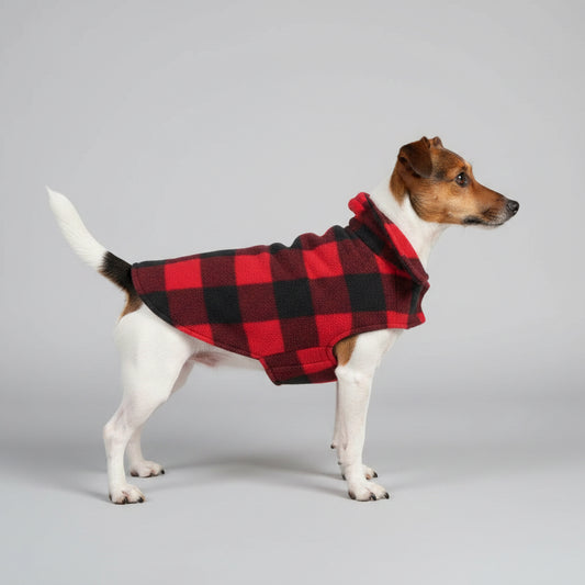Dog wearing a red and black checkered coat sitting on a pet bed in a car.